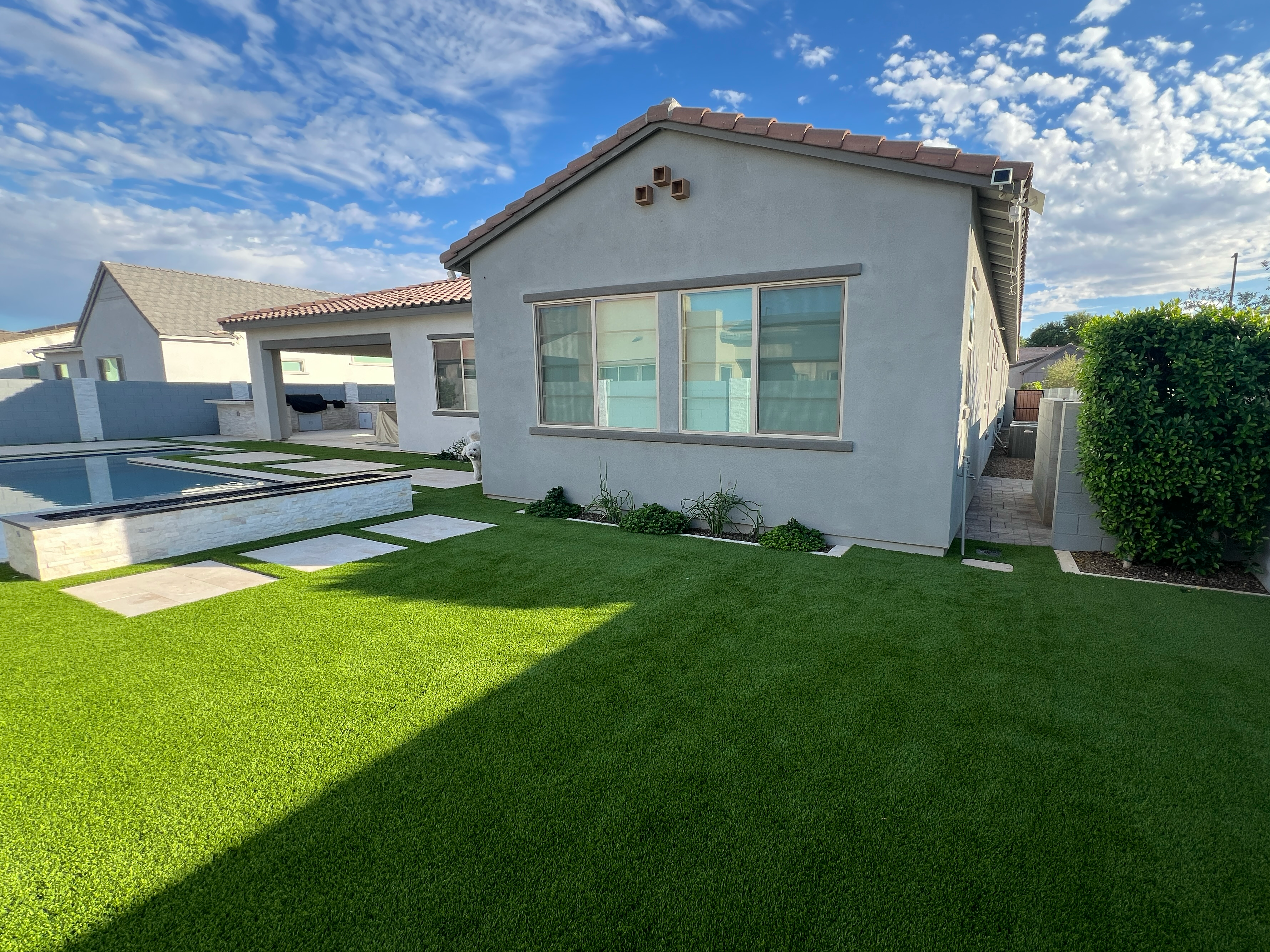 Modern house with a pool and well-maintained lawn under a blue sky.