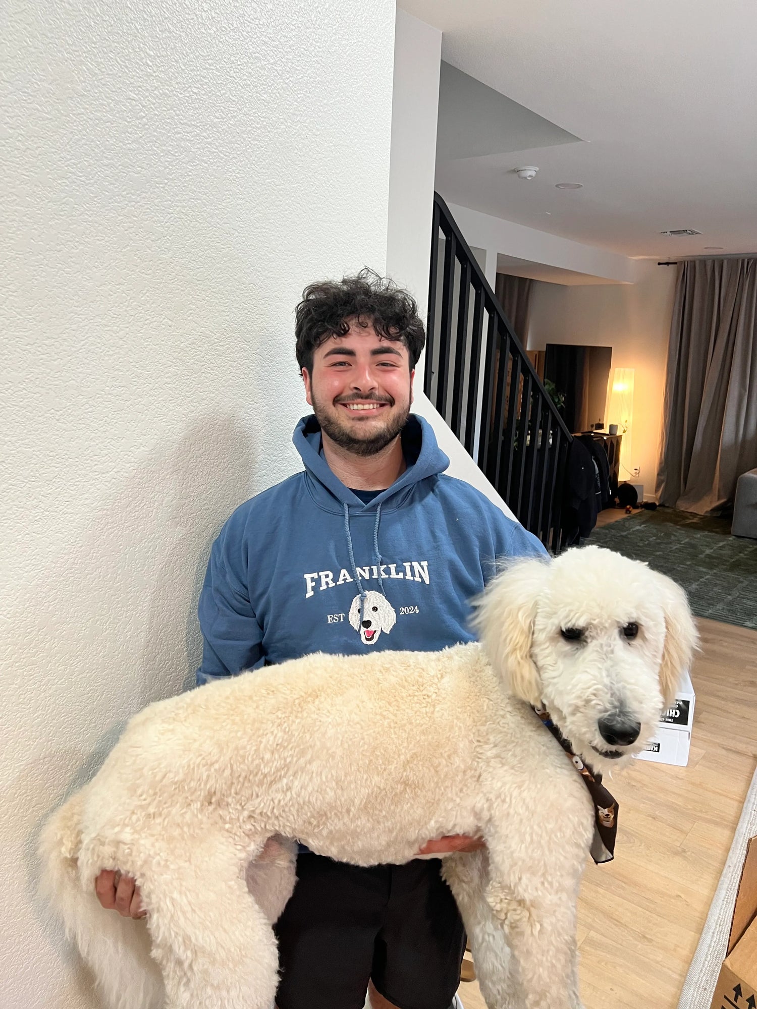 Man holding a white poodle in a home setting