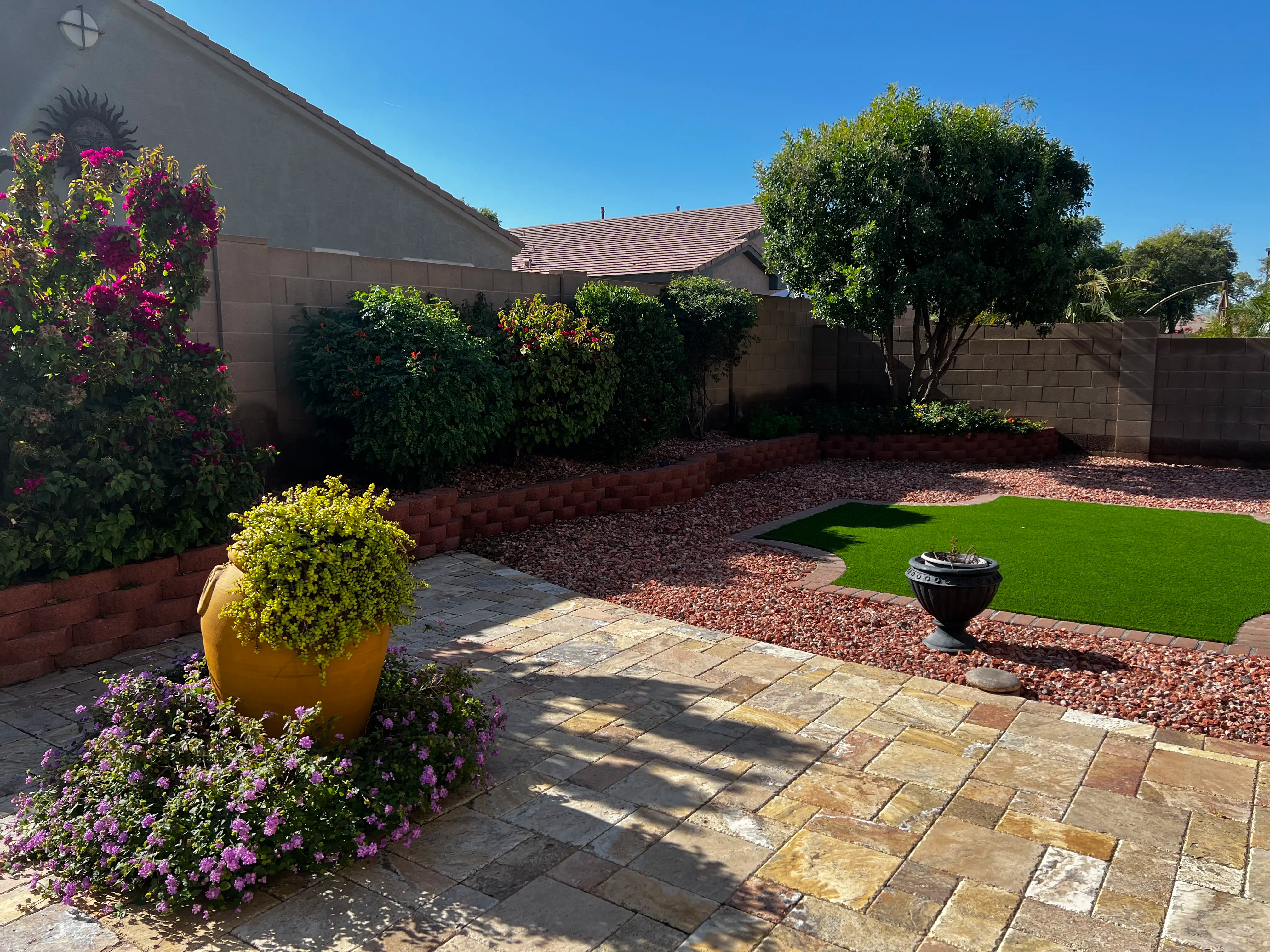 Backyard with patio, grass area, and decorative elements on a sunny day.